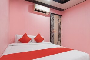 Una habitación con una cama, una puerta con un diseño decorativo y un equipo de aire acondicionado en la pared.