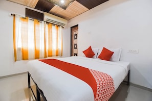 Ein Hotelzimmer mit Bett, Vorhängen, einer Klimaanlage und einer Tür.