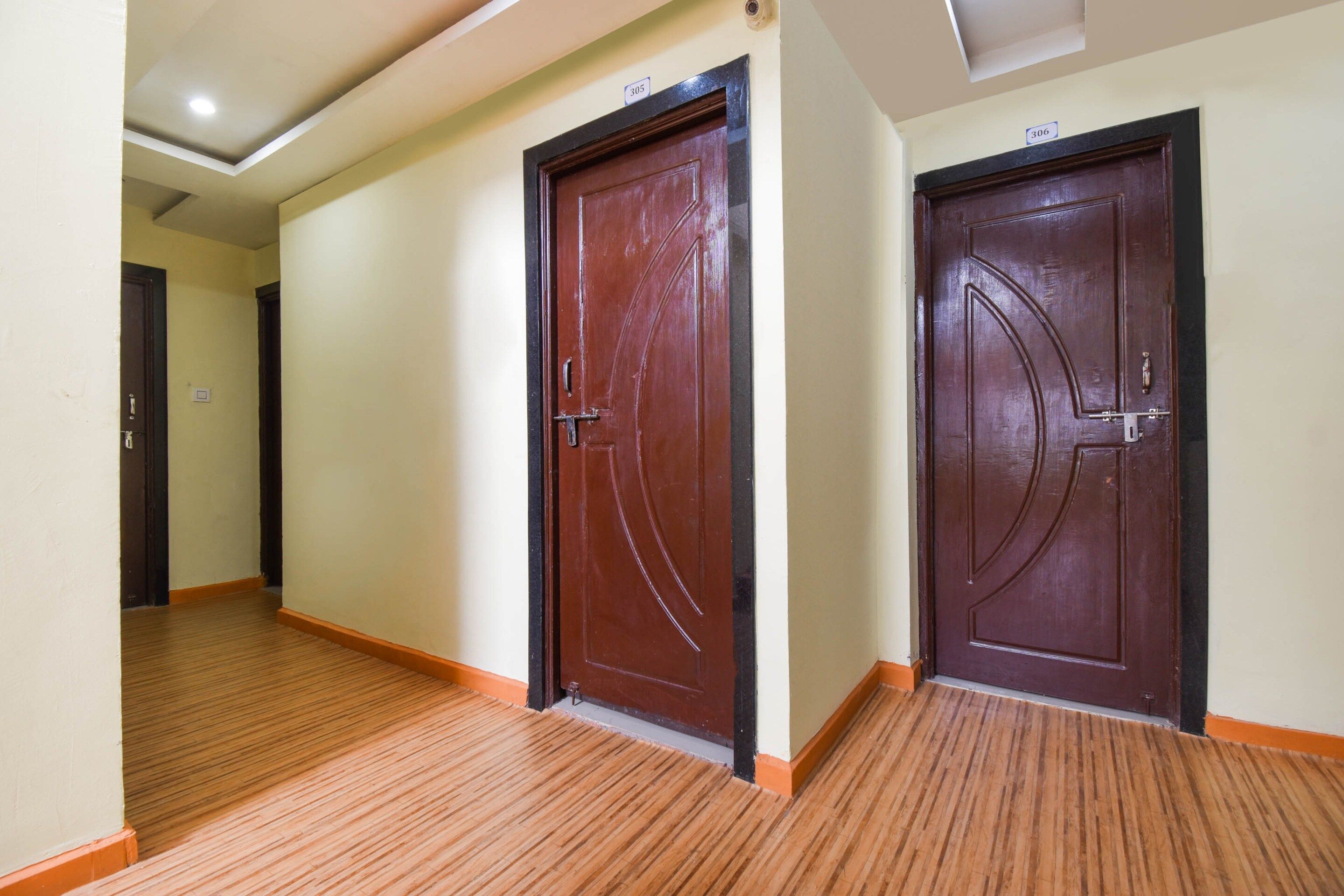A hallway with wooden flooring and two dark wooden doors with metal handles.
