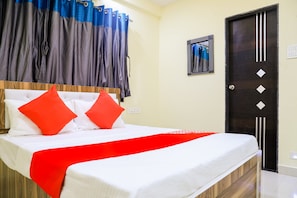 A hotel room with a bed, a red and white bedspread, and a black door. - Hotel O Pritesh Inn (Nagpur)