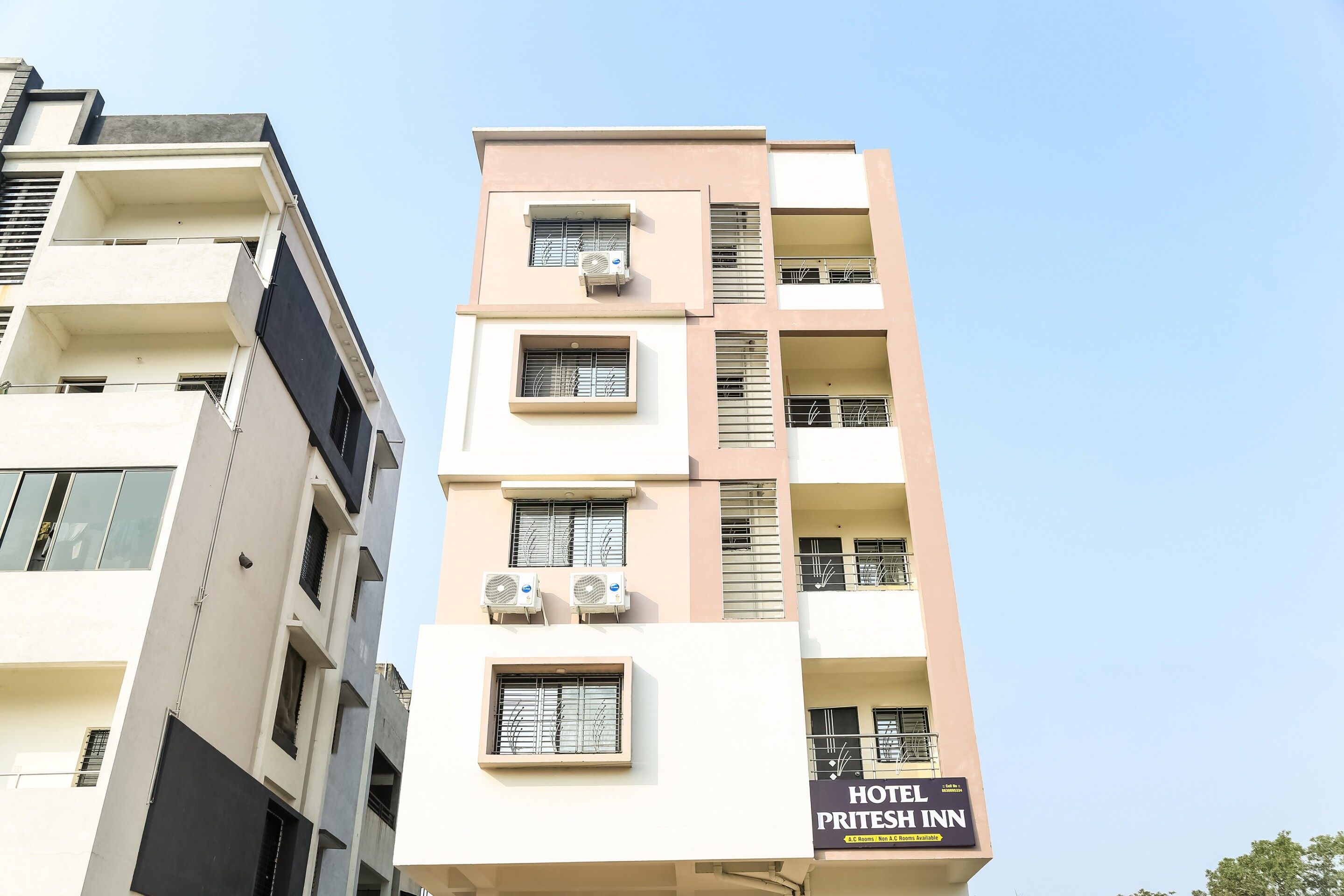 Un edificio de varios pisos con balcones y unidades de aire acondicionado.