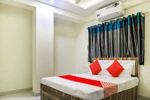A hotel room with a bed, curtains, and an air conditioning unit. - Hotel O Pritesh Inn (Nagpur)
