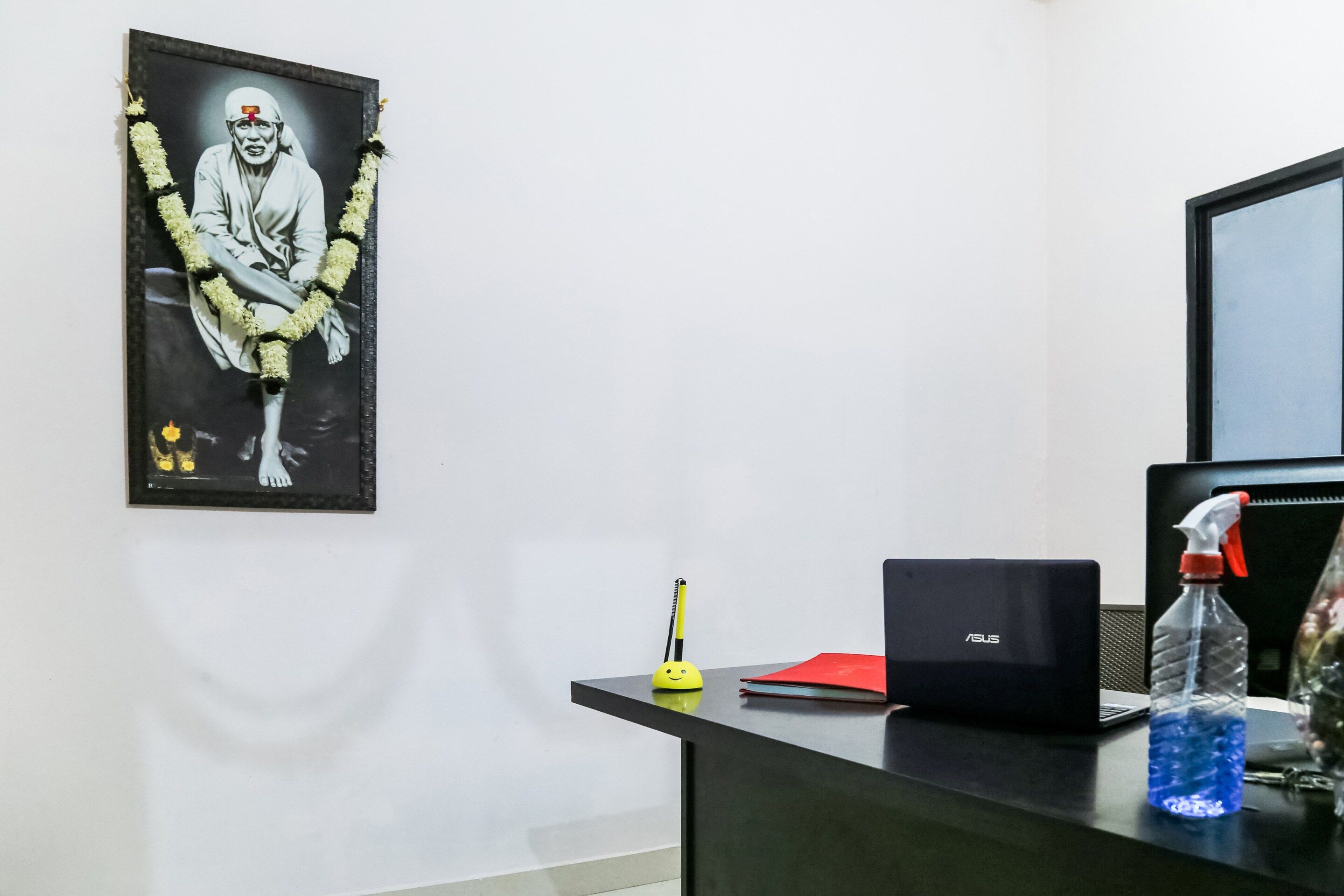 Uma mesa com um laptop, uma garrafa de água, uma pasta vermelha e uma caneta.