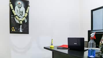 Uma mesa com um laptop, uma garrafa de água, uma pasta vermelha e uma caneta.