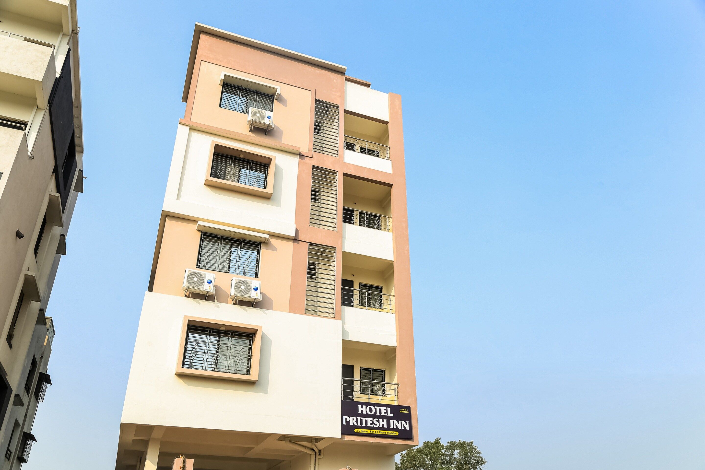 A multi-story building with a sign for 'Hotel Prithesh Inn' indicating A.C. rooms are available.