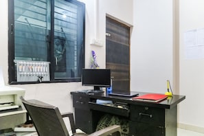A desk with a computer, a red notebook, and a yellow lamp. - Hotel O Pritesh Inn (Nagpur)