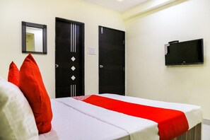 Quarto de hotel com cama, duas portas, espelho e televisão.