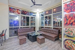 A modern living room with a sectional sofa, a glass coffee table, and a ceiling fan. - Hotel O Gkumar Restro (Nagpur)
