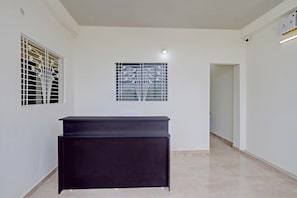 A room with a black cabinet, a window with a metal grille, and a door leading to another room. - Hotel O Casino (Kamptee)