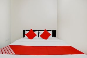 A bed with a white and red bedspread, two red pillows, and a black headboard. - Hotel O Casino (Nagpur)