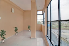 Una habitación amplia con ventanas grandes, piso de baldosas y dos plantas en macetas.