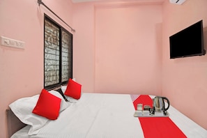 A single bed with red and white bedding, a window with a view, a flat-screen TV on the wall, and a tray with a kettle and cups. - Hotel O R K Guest House (Nagpur)