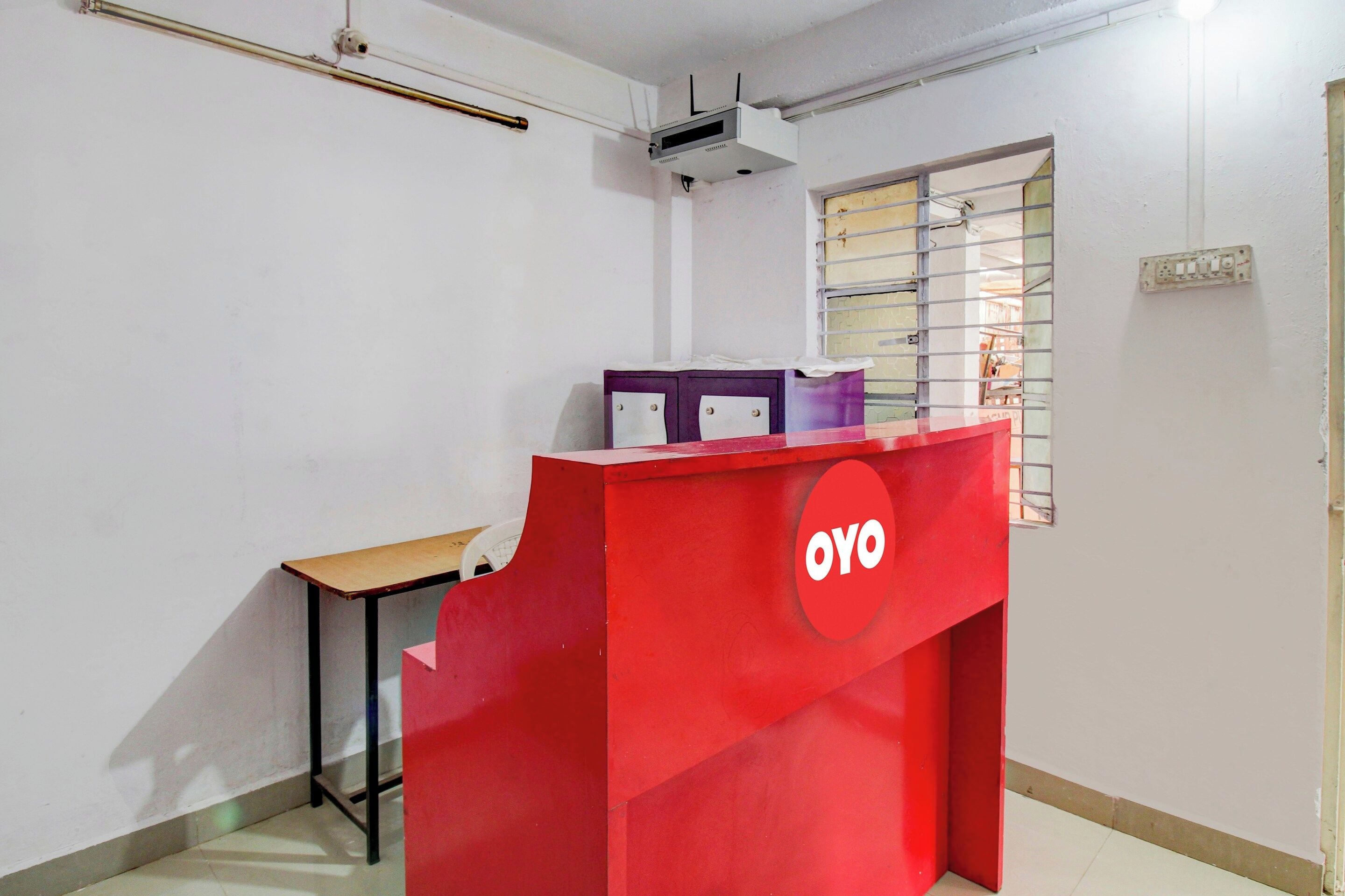 En röd receptionsdisk med ett fönster och ett litet bord.