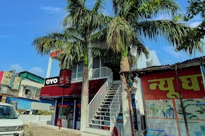 A commercial building with a prominent OYO sign, a staircase, and a parked car. - Hotel O The Golden Key (Nagpur)