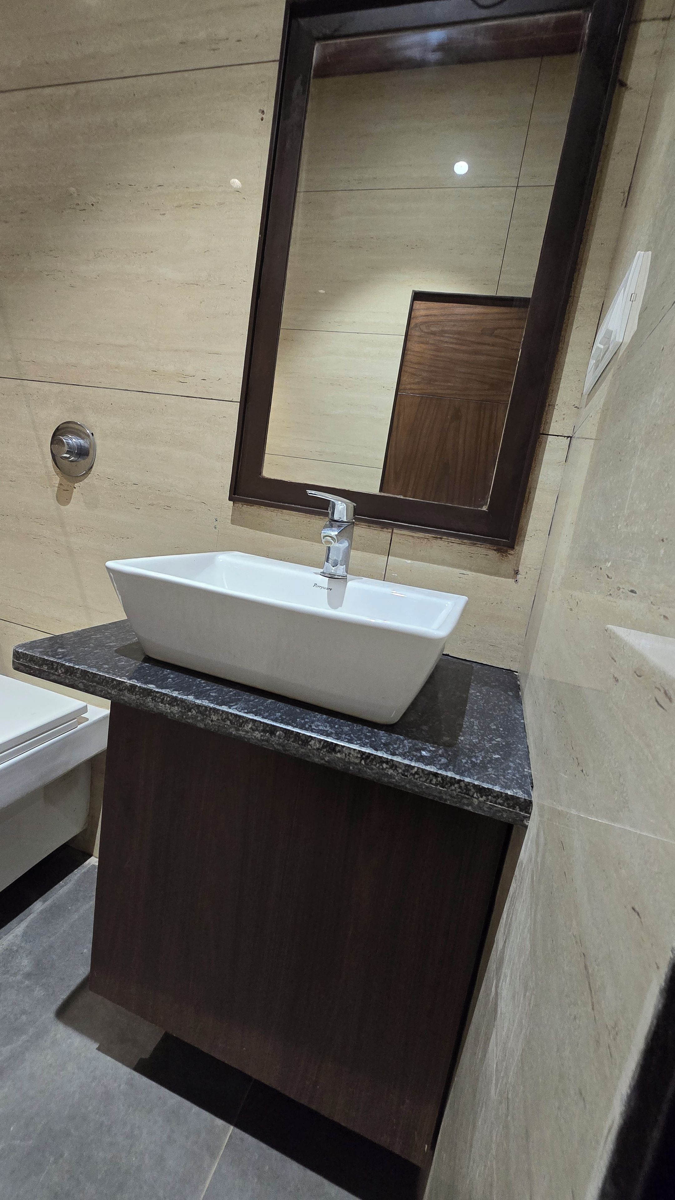 A bathroom with a rectangular sink, a mirror, and a marble countertop.