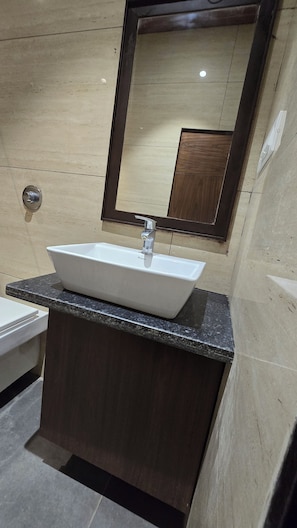 Un baño con un lavamanos rectangular, un espejo y una encimera de mármol.