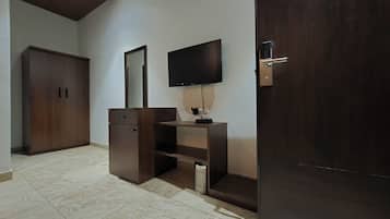 A room with a wooden wardrobe, a TV mounted on the wall, and a door with a modern handle.