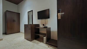 Habitación con un armario de madera, televisor montado en la pared y una puerta con picaporte moderno.