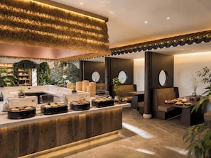 Een moderne hotellobby met een receptiebalie, een zithoek en decoratieve planten.