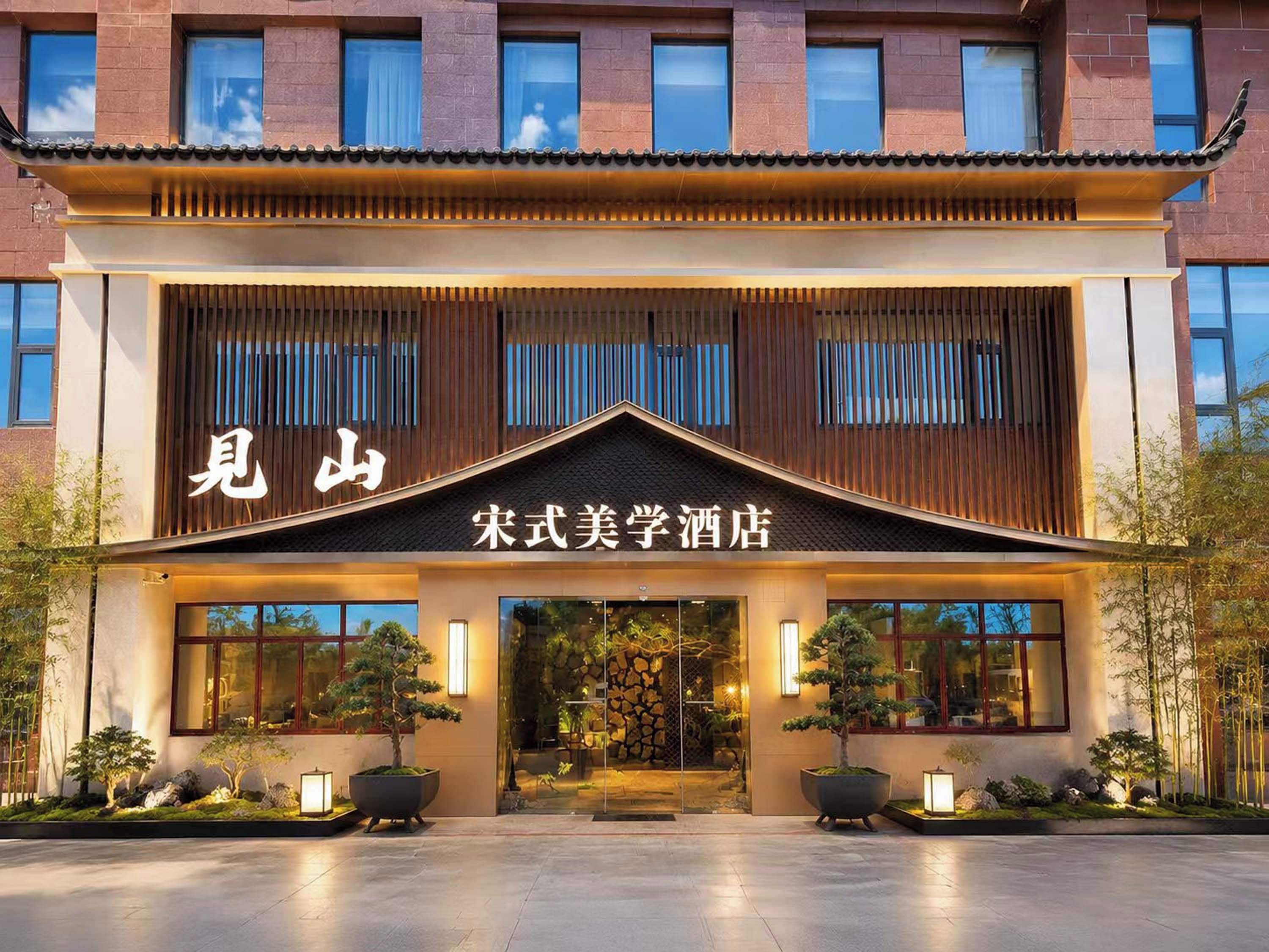 Een hotelgevel in traditionele Chinese architectuur, met een opvallend bord en een goed verlichte gevel.