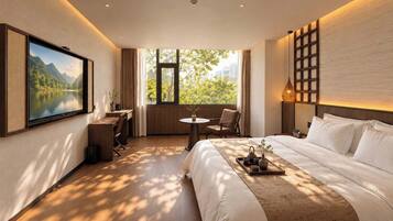 A hotel room with a bed, a desk, a chair, a TV, and a window with a view of greenery.