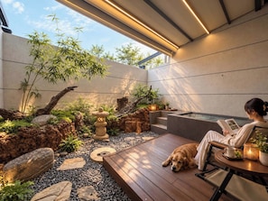 Een modern buitenterrein met zitgedeelte, een hond, iemand die leest en een kleine waterpartij.