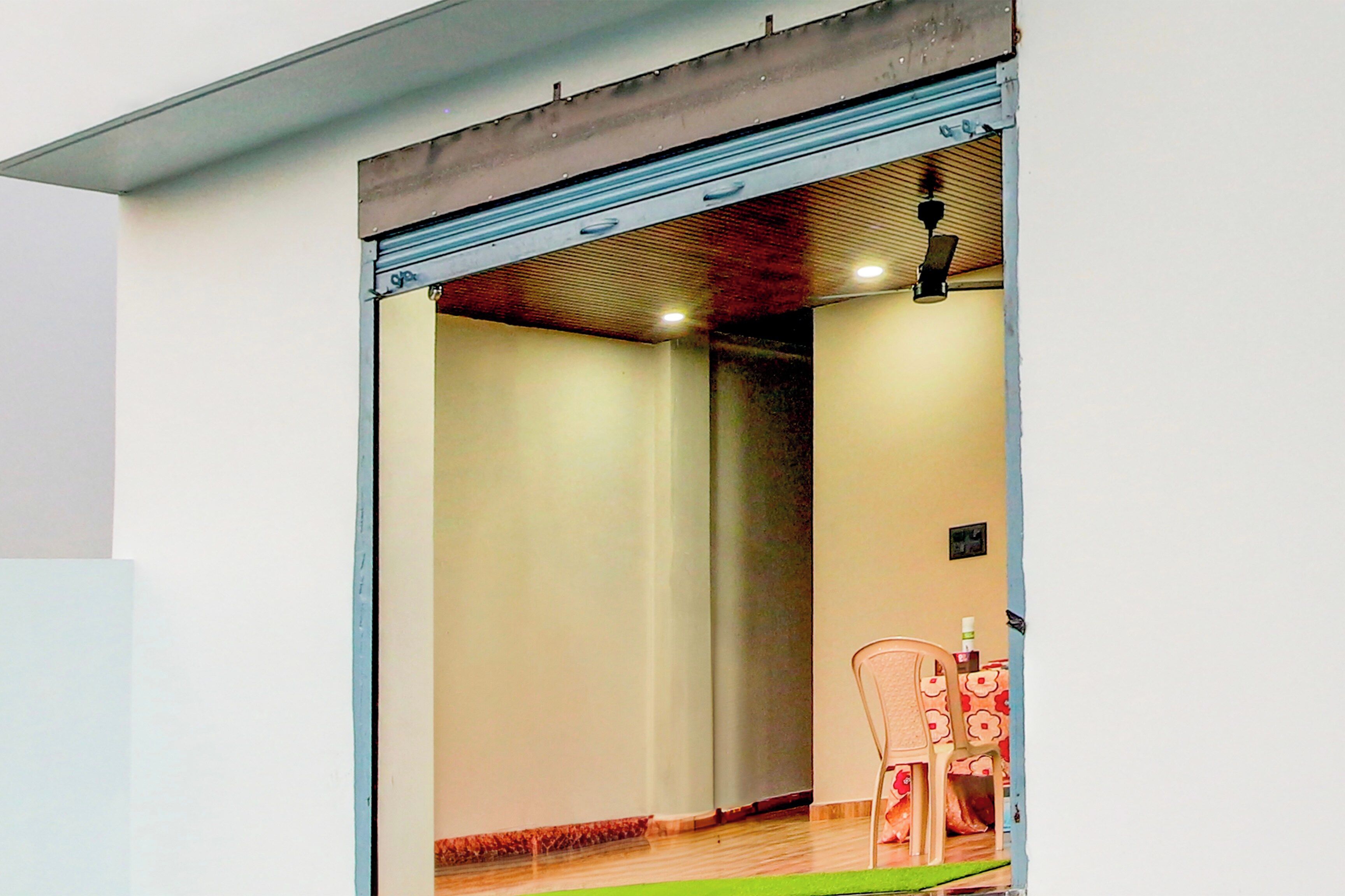A doorway leading to a room with a wooden floor, a chair, and a small table.