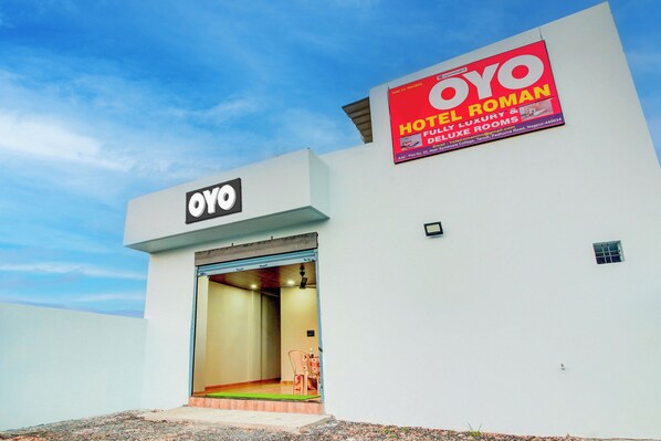 Un edificio con un letrero que indica que es un hotel OYO Roman, que ofrece habitaciones de lujo y superiores.