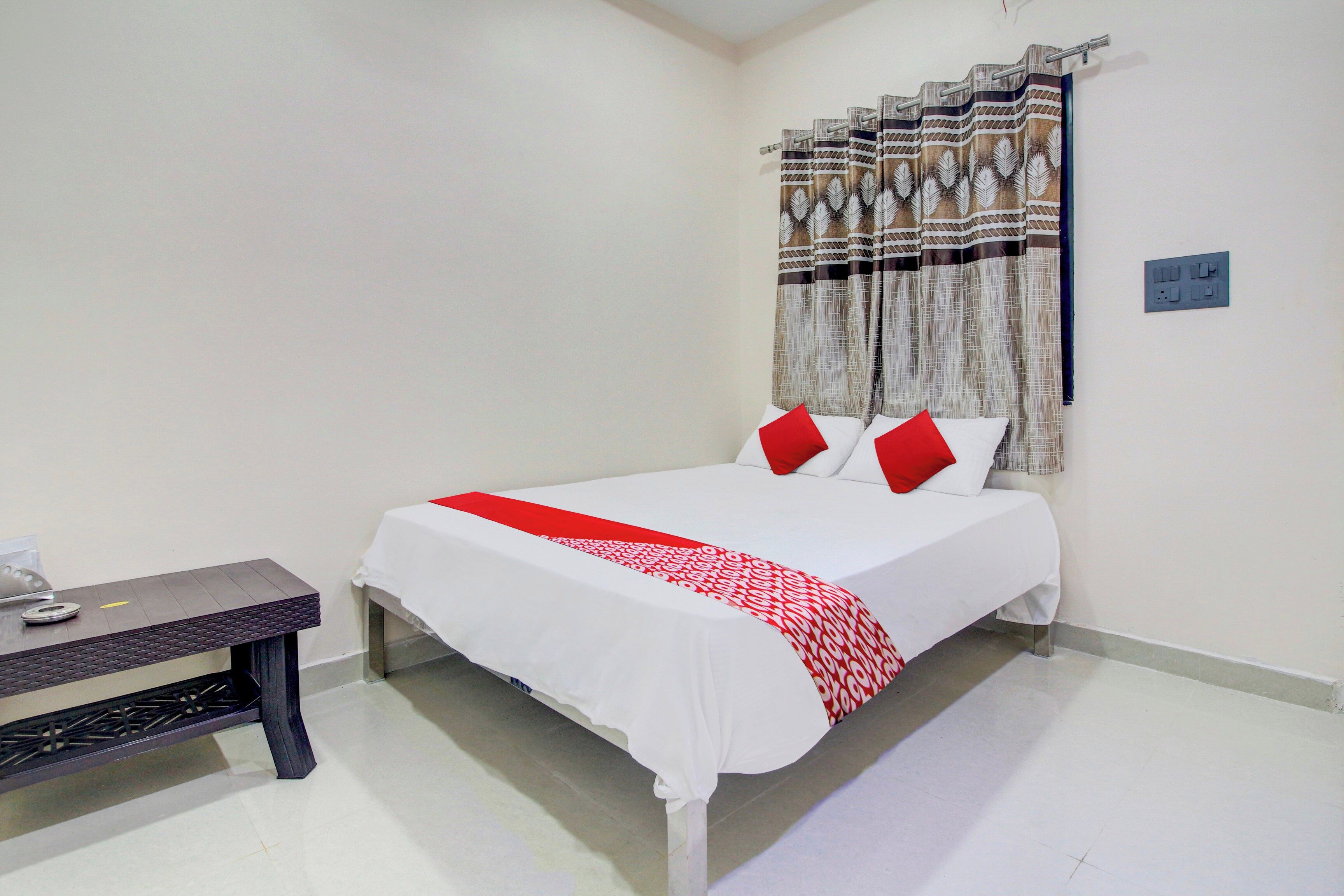A hotel room with a bed, a bedside table, and a curtain.