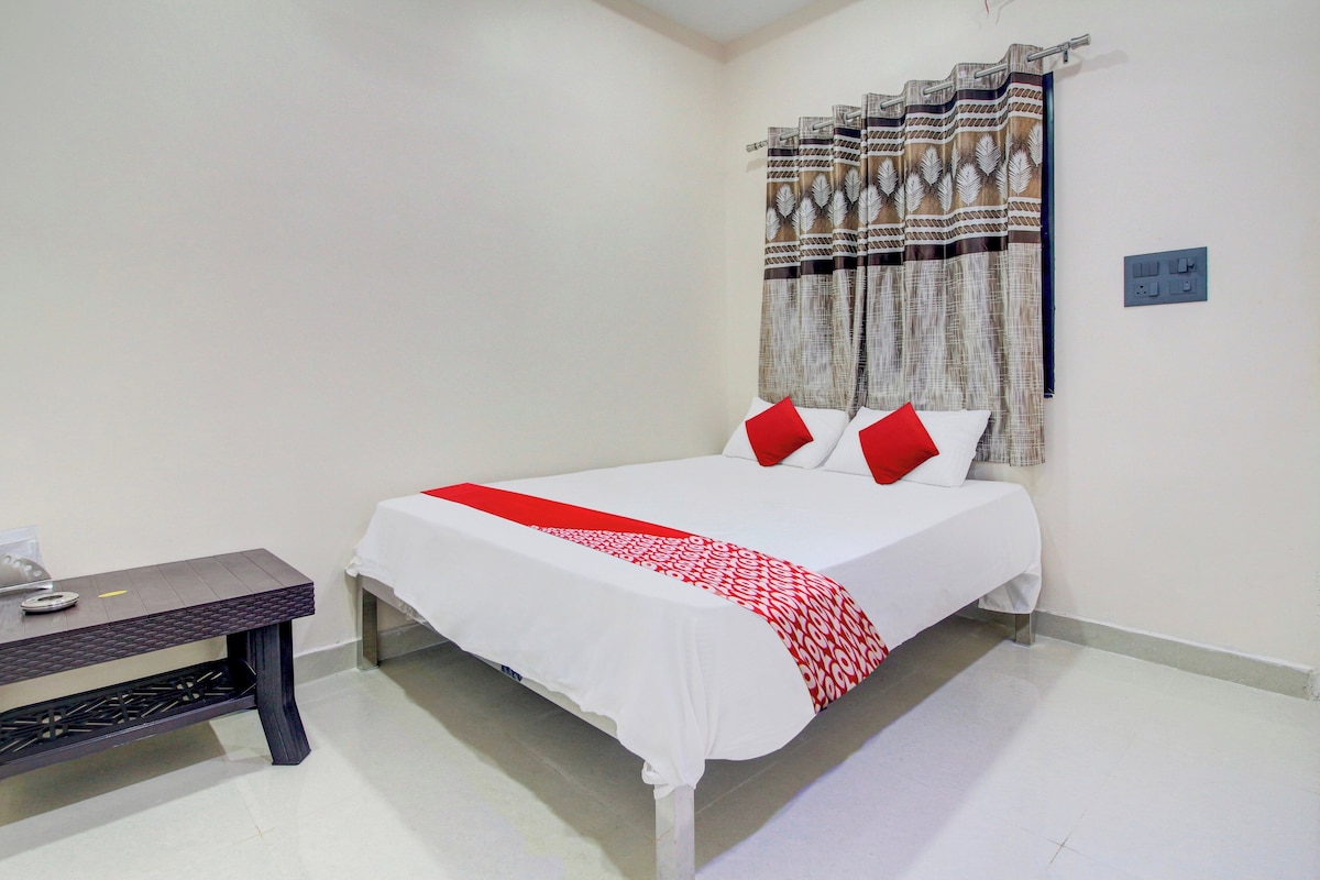 A hotel room with a bed, a bedside table, and a curtain.