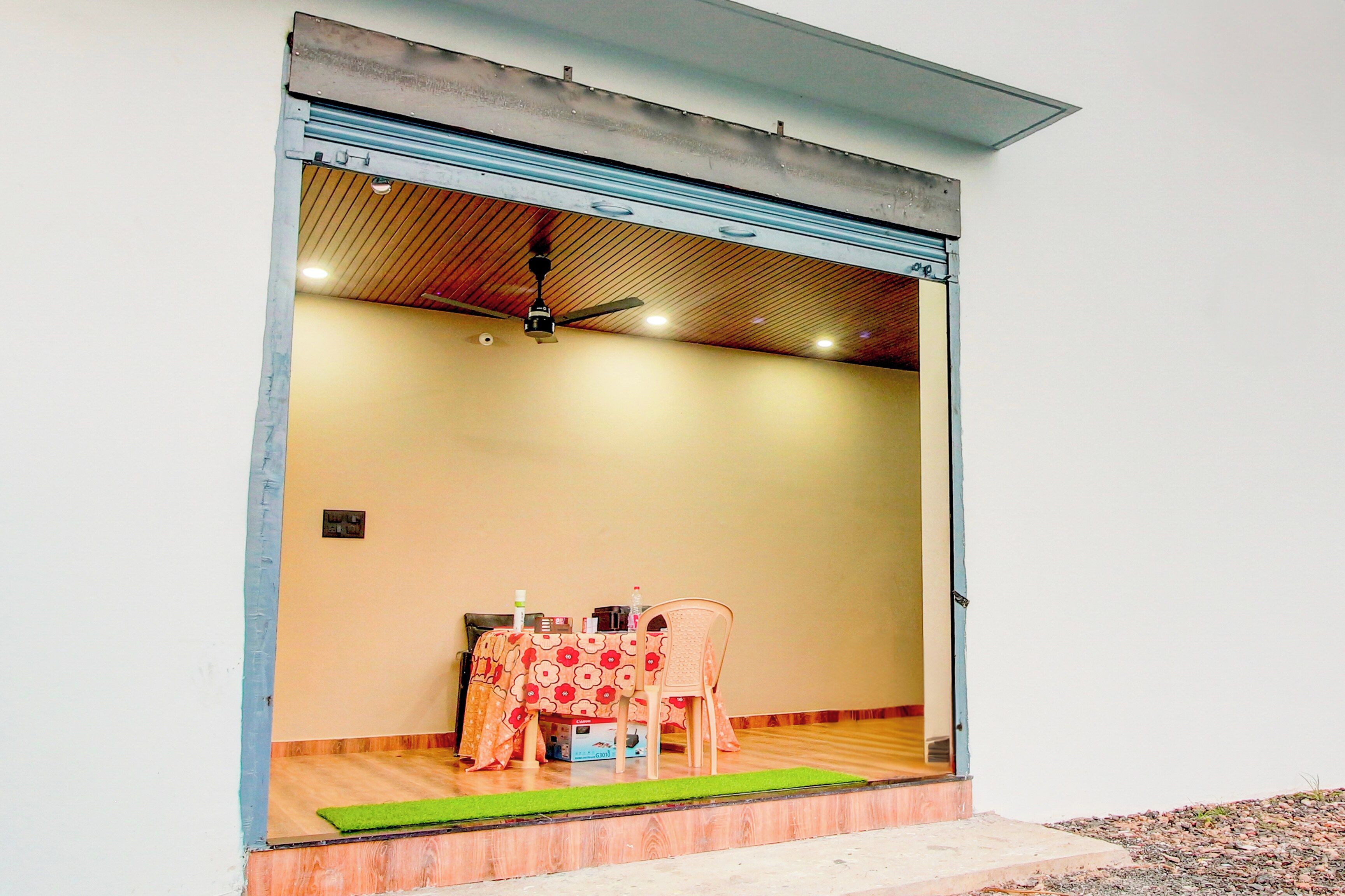 A room with a closed sliding door, a ceiling fan, a table with chairs, and a small rug on the floor.