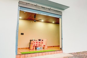 A room with a closed sliding door, a ceiling fan, a table with chairs, and a small rug on the floor. - Hotel O by OYO Roman Inn (Nagpur)