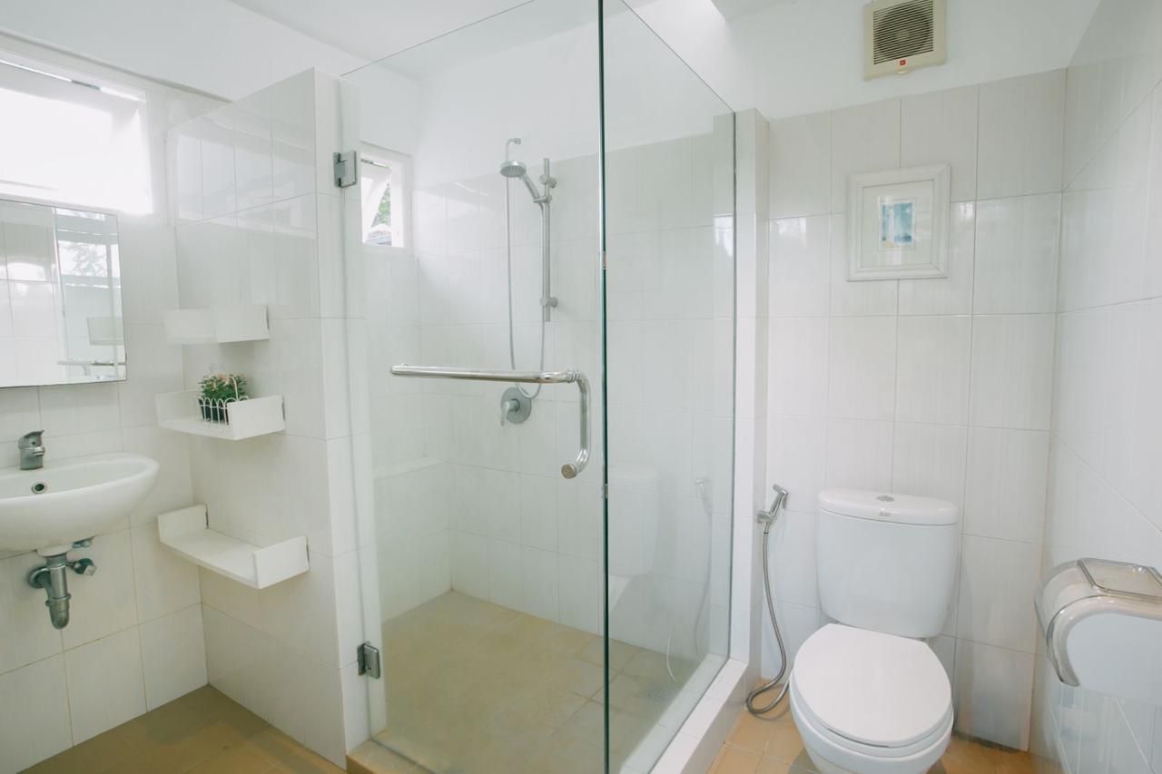 A modern bathroom with a glass-enclosed shower, a toilet, and a sink.
