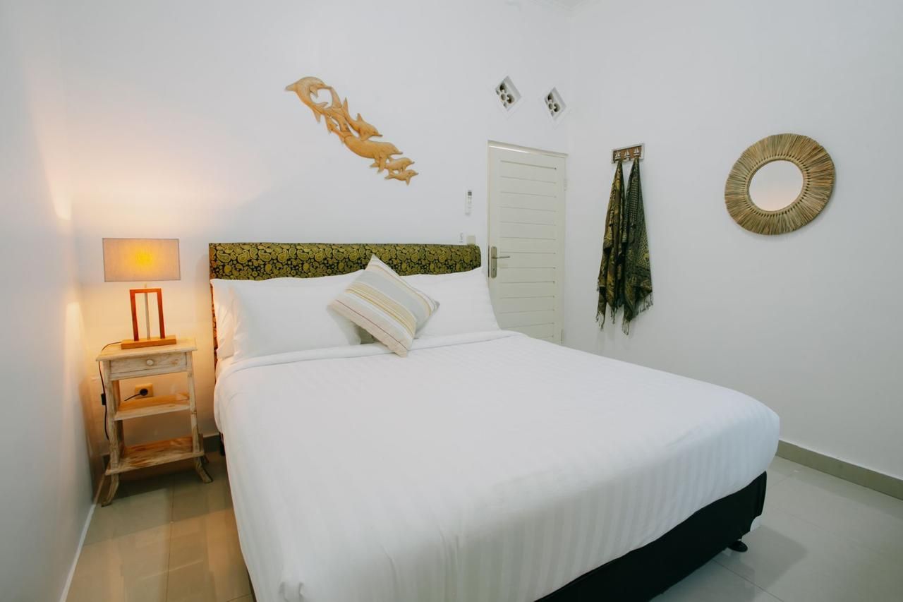 Ein Schlafzimmer mit Bett, Nachttisch, Lampe, einer Tür und Wanddekorationen.