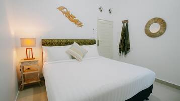 Ein Schlafzimmer mit Bett, Nachttisch, Lampe, einer Tür und Wanddekorationen.