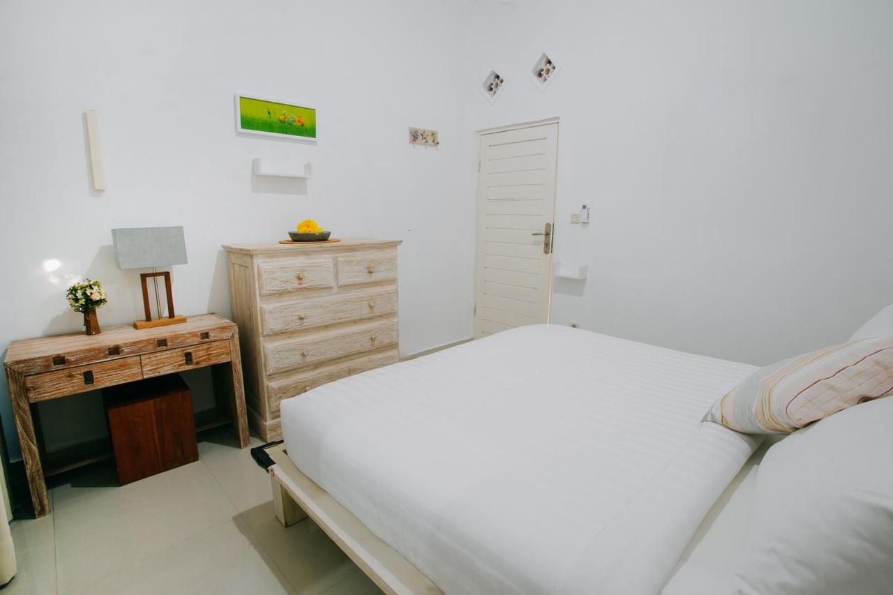 A bedroom with a bed, a dresser, a desk, and a lamp.