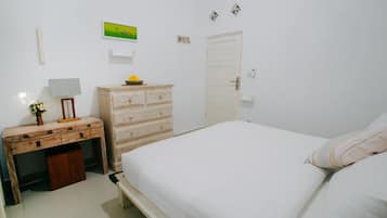 A bedroom with a bed, a dresser, a desk, and a lamp.