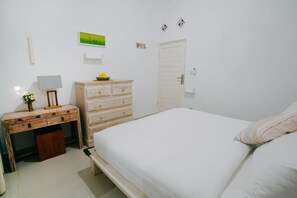 Une chambre à coucher avec un lit, une commode, un bureau et une lampe.