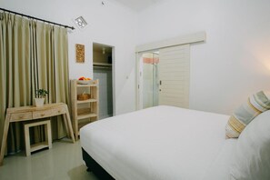 A bedroom with a bed, a desk, a wardrobe, and a shelf with items. - House in the Bush (Badung)