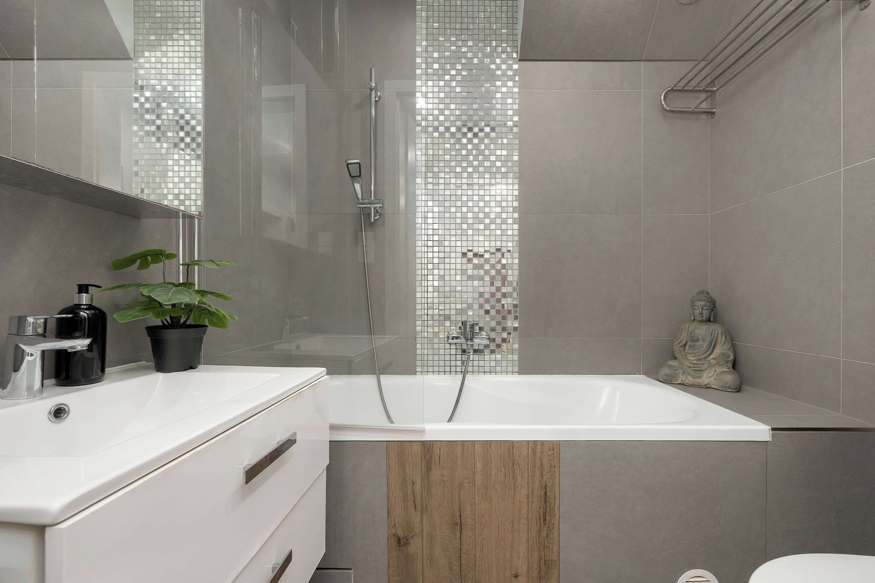Een moderne badkamer met een ruime witte badkuip, een douche met glazen wanden en een houten accentpaneel.