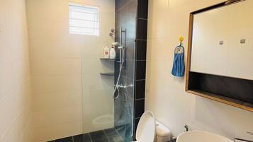 Un baño con inodoro, lavabo y zona de ducha.