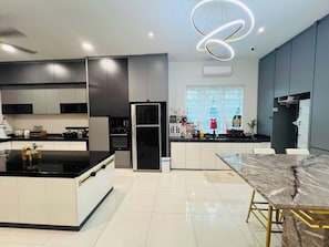 Una cocina moderna con una isla central, electrodomésticos integrados y un comedor con mesa de mármol.