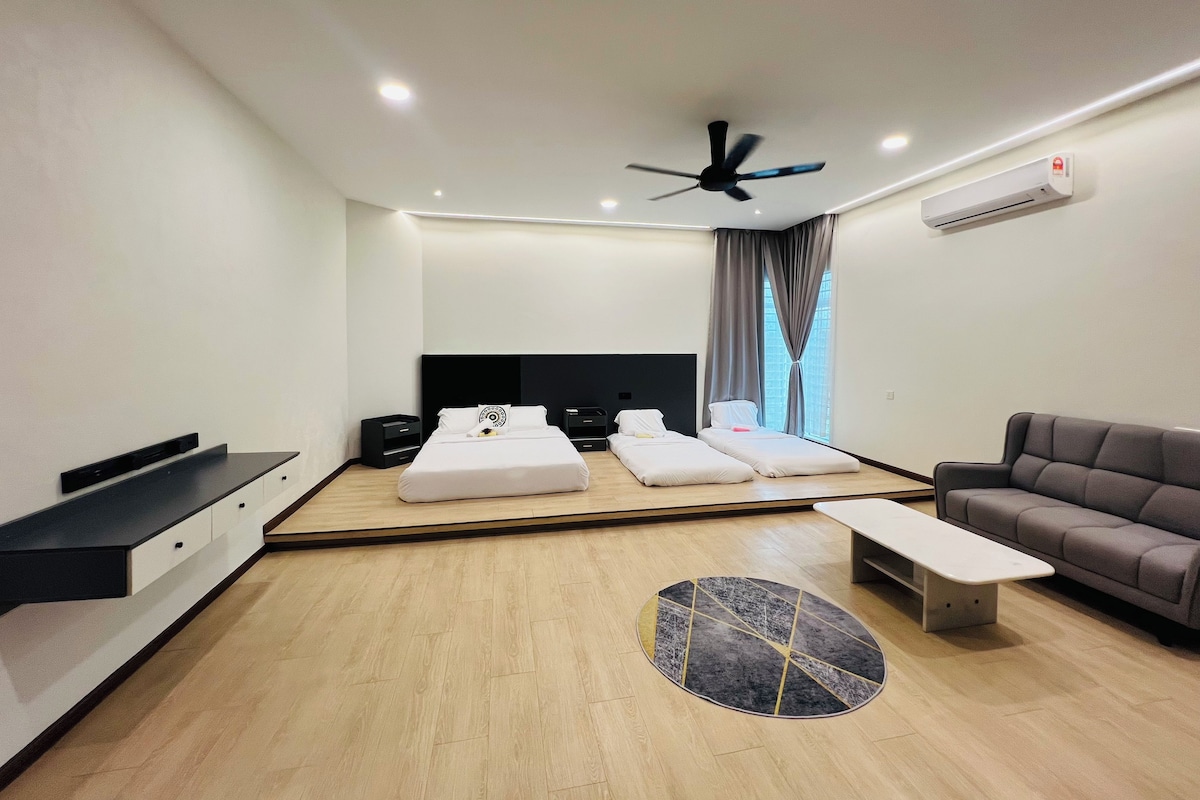 Habitación de hotel moderna con cama, sofá, mesa de centro, televisor y aire acondicionado.