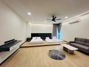 Habitación de hotel moderna con cama, sofá, mesa de centro, televisor y aire acondicionado.