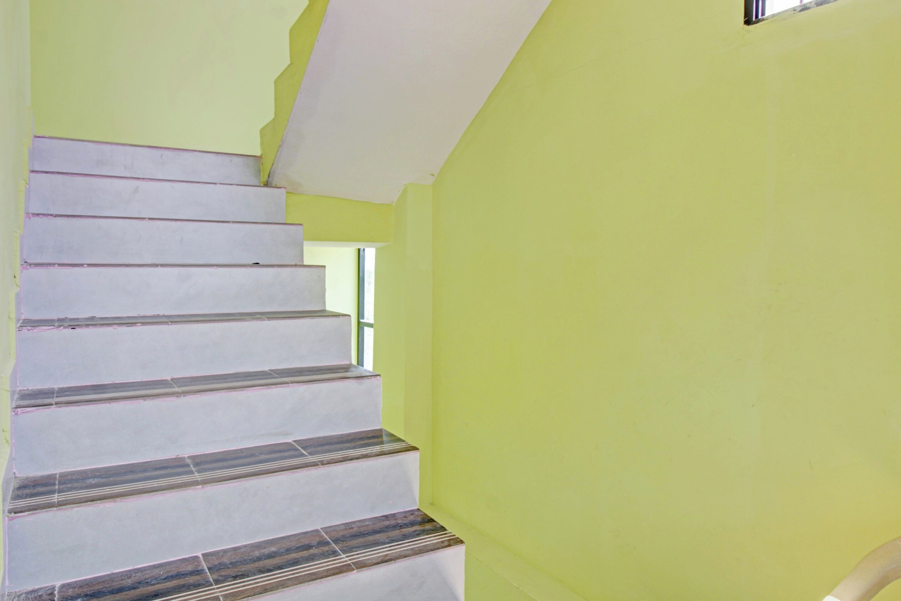 A staircase with a white and grey patterned floor leading to a room with a green wall.