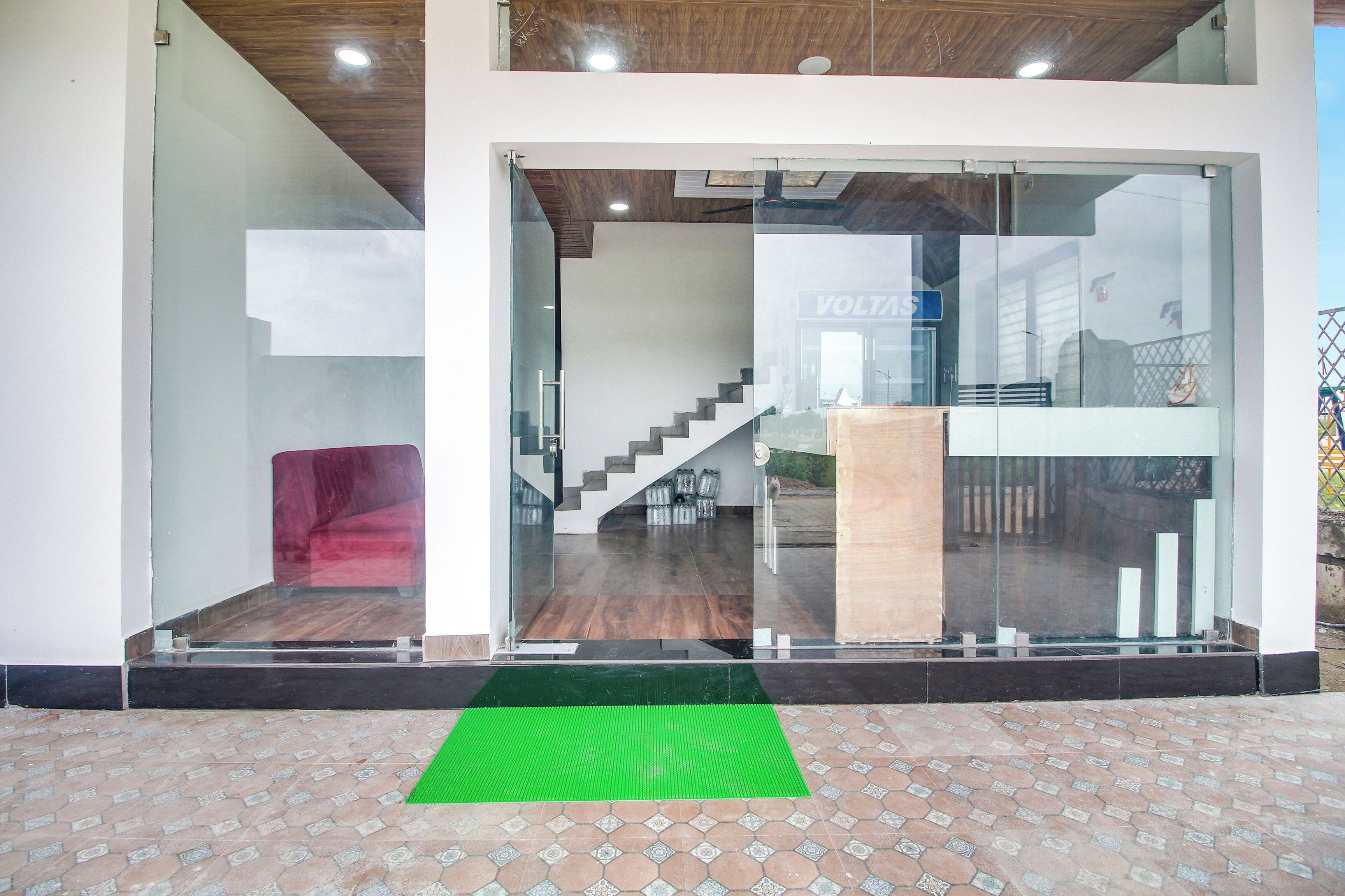 A modern building entrance with glass doors, a staircase, and a red chair.