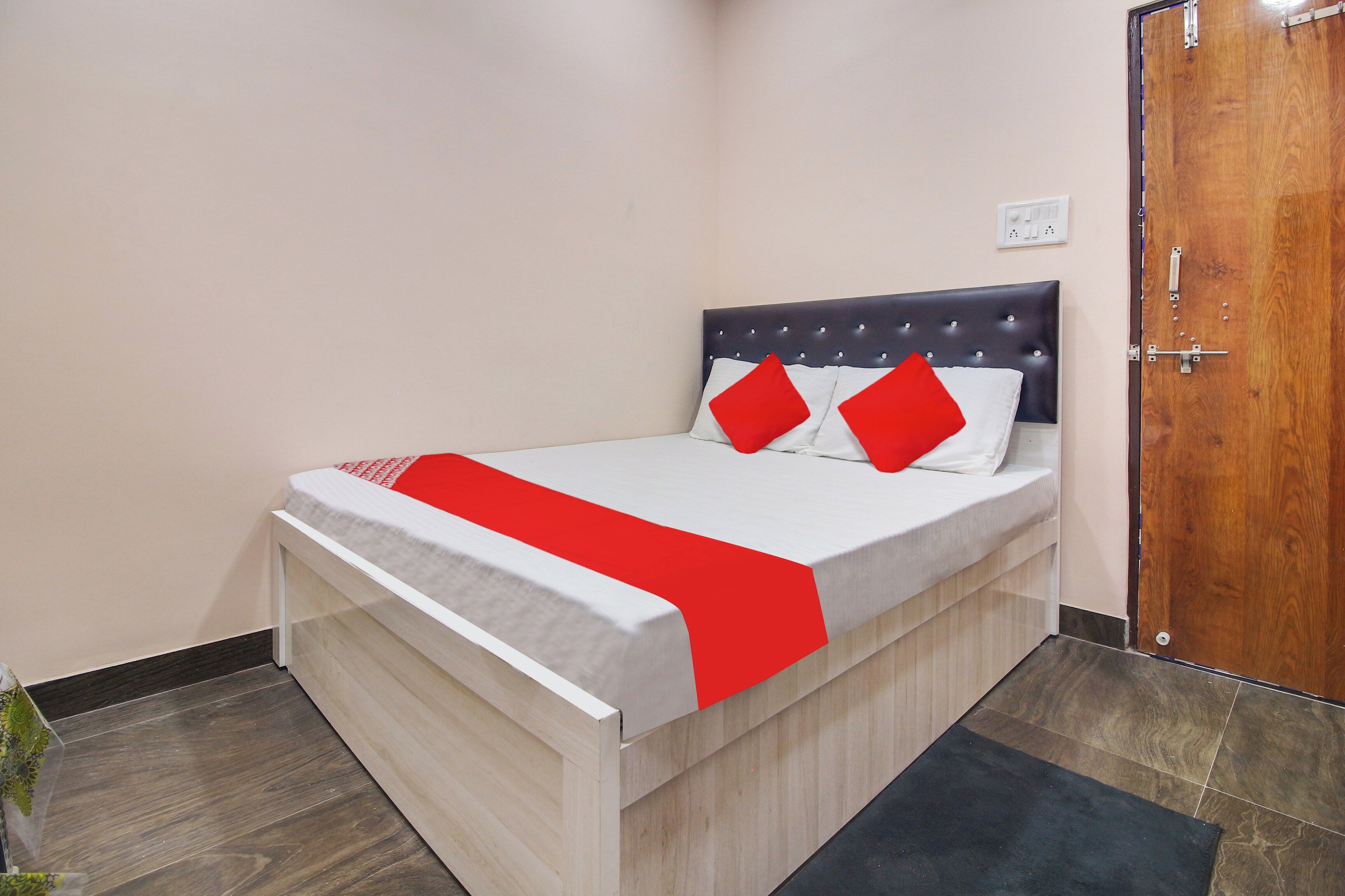A neatly made bed with a white and red bedspread, two red pillows, and a dark headboard.