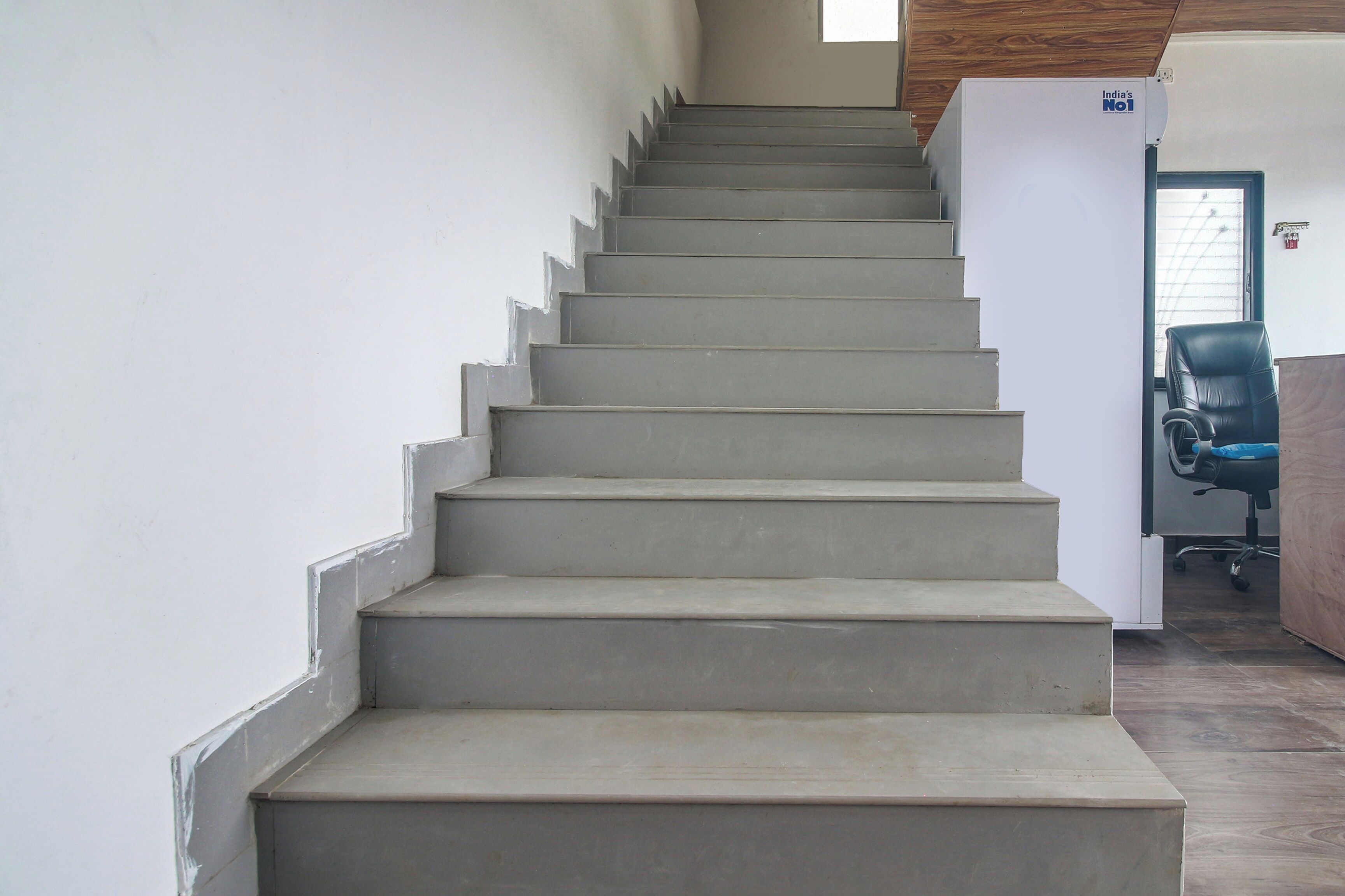 A staircase leading to a landing with a door and a chair.