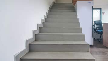 A staircase leading to a landing with a door and a chair.