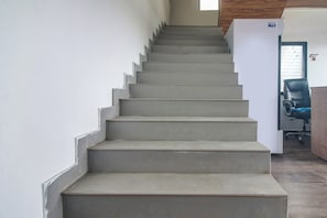 Uma escadaria que leva a um patamar com uma porta e uma cadeira.